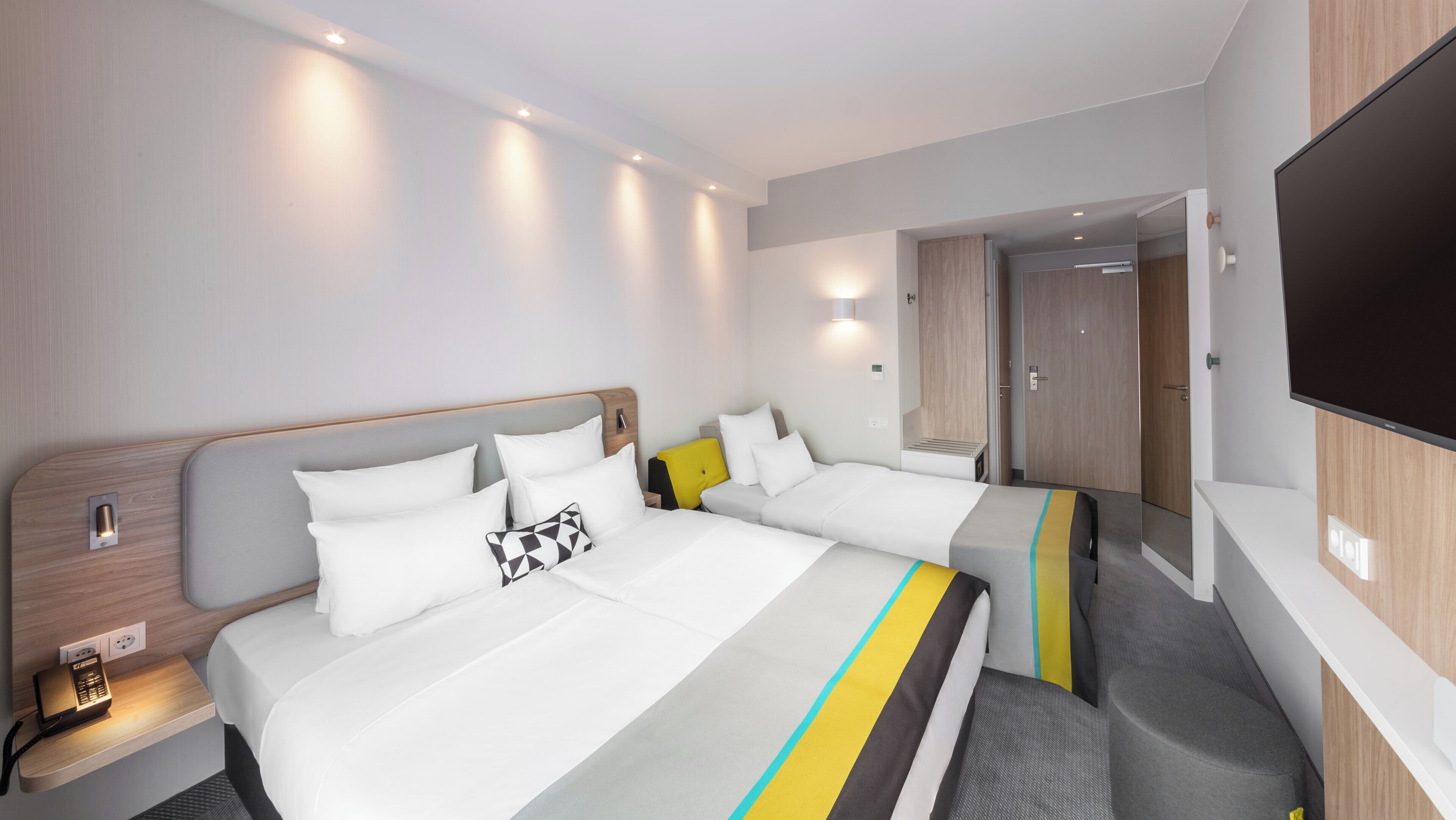 A hotel room with two beds, a TV, and a bedside table with a phone.