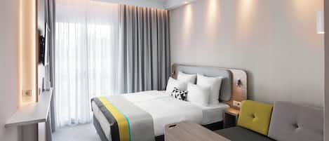 Una habitación de hotel con cama, mesita de noche, lámpara y una pequeña mesa de madera.