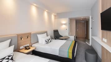 A modern hotel room with a bed, bedside tables, a chair, a desk, and a TV.