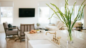 A kitchen with a marble countertop, gold faucets, and a vase with green plants. - Luxury in DT Tempe -2 en-suites - ASU, Spring Training, Golf & More (Tempe)