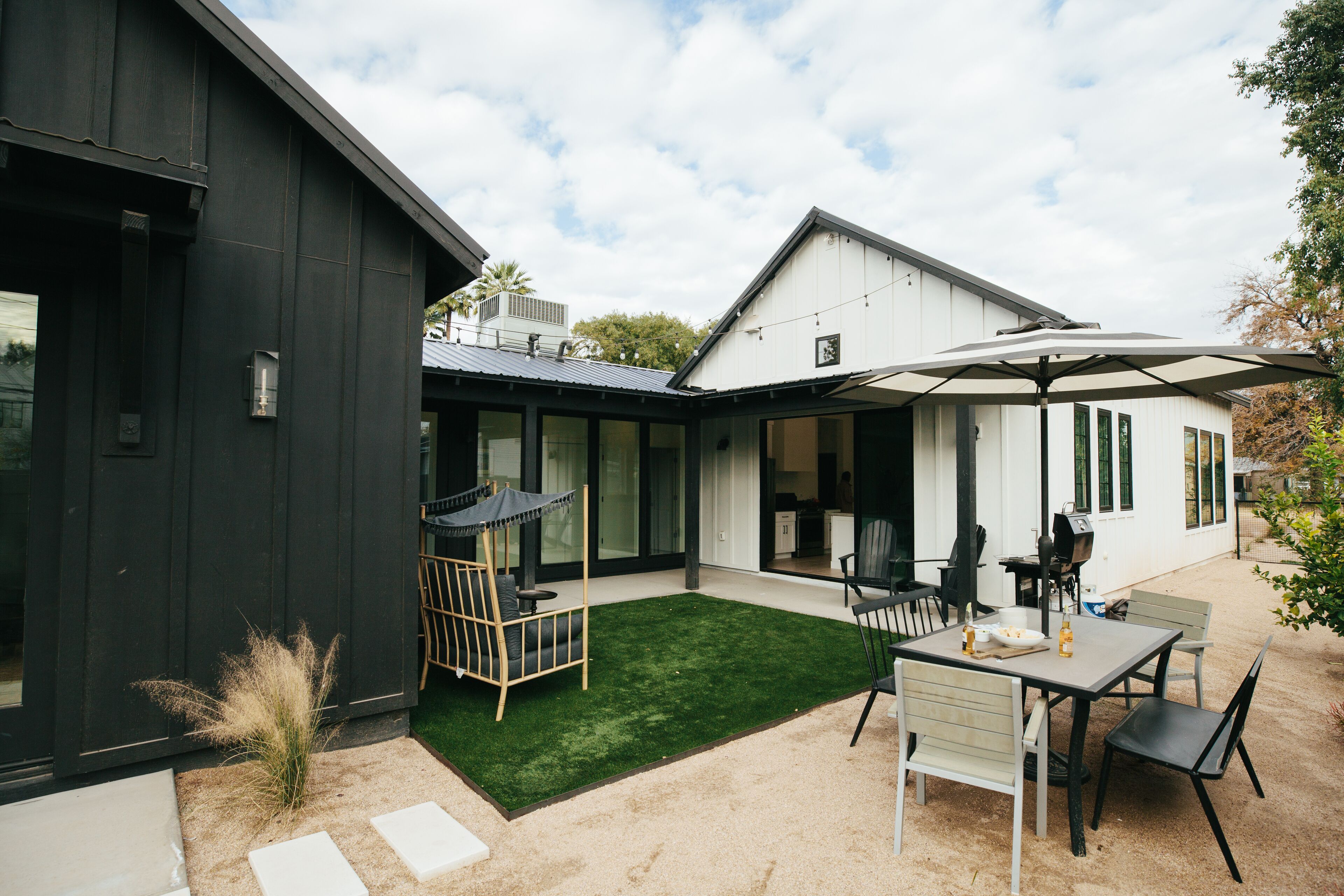 Een modern huis met een patio, compleet met een eettafel, stoelen en een schommelstoel.