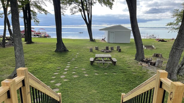 Eine Holzterrasse führt zu einer Rasenfläche mit Picknicktisch und kleiner Gartenhütte.