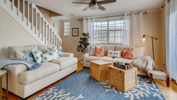 A living room with a staircase, a ceiling fan, a sofa set, a coffee table, and a floor lamp. - Spacious and Charming 2 level beach condo (Lauderdale-by-the-Sea)