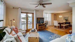 A spacious living room with a large sofa, a television, and a dining area with a table and chairs. - Spacious and Charming 2 level beach condo (Lauderdale-by-the-Sea)