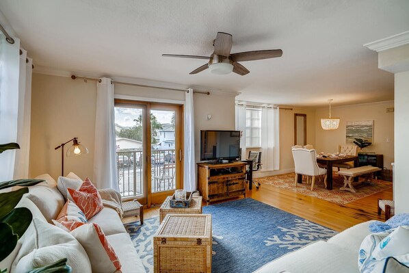 A spacious living room with a large sofa, a television, and a dining area with a table and chairs.