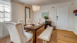 A dining area with a wooden table set for four, surrounded by upholstered chairs. A chandelier hangs from the ceiling, and a painting is on the wall. - Spacious and Charming 2 level beach condo (Lauderdale-by-the-Sea)