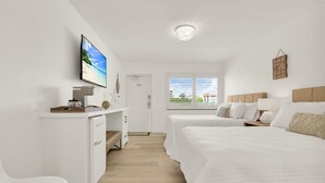 Habitación de hotel con cama, escritorio, televisión y ventana con vista a la playa.