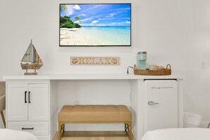 A bedroom with a bed, a small cabinet, a bench, a wall-mounted picture, and a shelf with a coffee maker and a basket. - Boutique Hotel 2 double beds with POOL, LOCATION! 1 block to BEACH/Restaurants (Deerfield Beach)