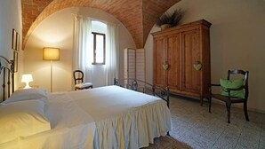 A bedroom with a bed, a wooden cabinet, a chair, and a lamp. - Bella Valle 3 Campagna, Relax in Giardino, Mare a 2 km e la Toscana Tuta Intorno (Toscana)