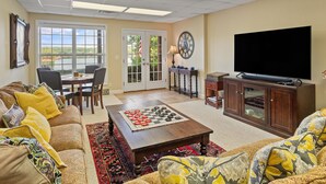 A living room with a large TV, a chessboard, and a dining area with a view of the outdoors. - Blue Door - Entertainment area downstairs with a pool table (Arley)