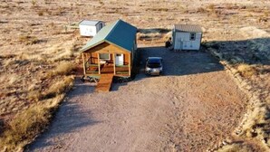A small wooden cabin with a porch, a car parked in front, and a small shed nearby. - Private RV Site with Personal Observatory Access (Animas)