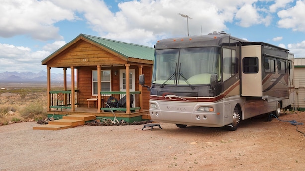 A small wooden cabin with a porch and a large RV parked in front. - Private RV Site with Personal Observatory Access (Animas)