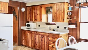 A kitchen with wooden cabinets, a microwave, a sink, and a dining area with chairs. - Book your SUMMER FUN now - lakes, waterfalls, ATV/UTV trails! Your fun awaits! (Crivitz)