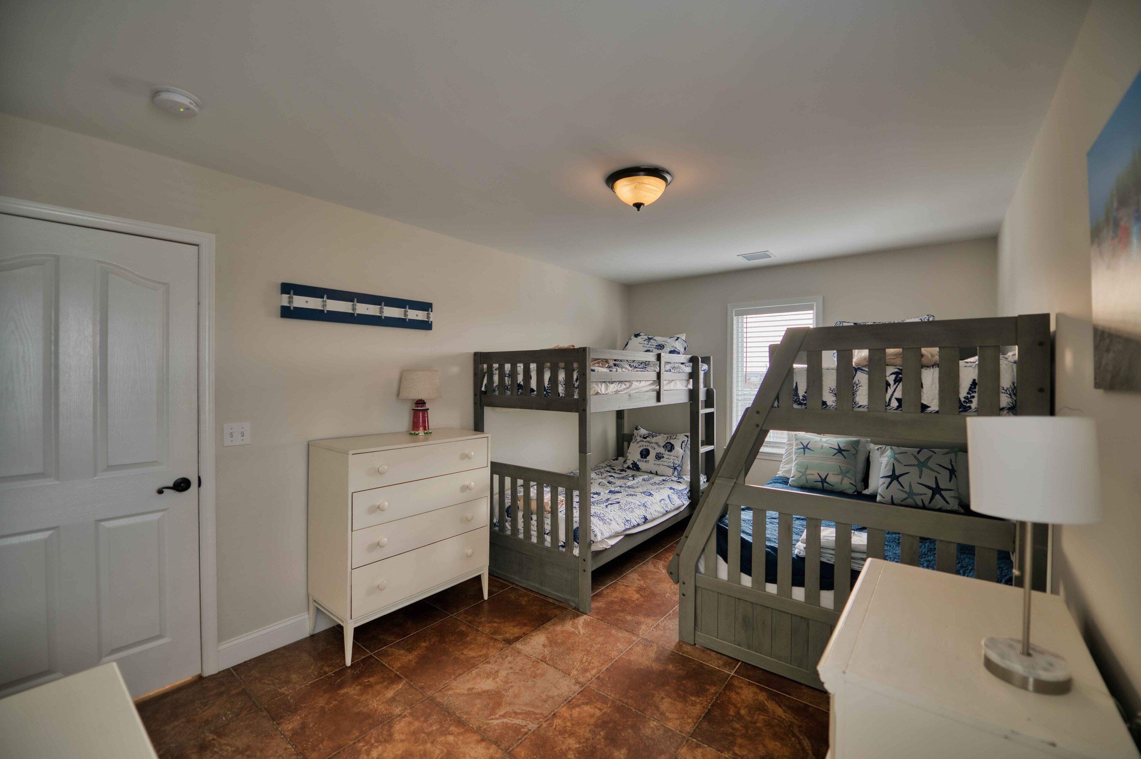 Un dormitorio infantil con literas, cómoda y lámpara en el techo.