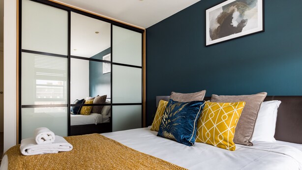 Une chambre d’hôtel avec un grand lit, une porte-fenêtre coulissante et une œuvre d’art encadrée au mur.