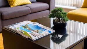 Un salon avec un canapé, une table basse sur laquelle sont posés des magazines et une plante en pot.
