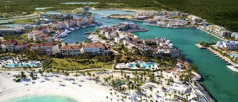 Vista aérea de un resort con varias construcciones, una playa y aguas turquesas cristalinas.