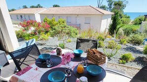 A table set outdoors with a view of a building and the sea. - T3 sea view - beach & pool with all comforts (Linguizzetta)