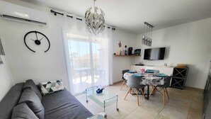 A modern living room with a sofa, dining table, and kitchen area. - T3 sea view - beach & pool with all comforts (Linguizzetta)