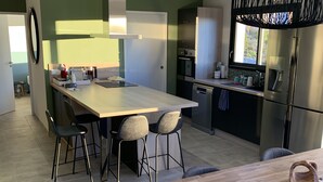 A modern kitchen with a central island, bar stools, a dining table, and a large refrigerator. - Vacation villa with private pool Lussan (near Uzès) (Lussan)