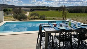 A poolside dining area with a table set for four, surrounded by chairs, overlooking a swimming pool. - Vacation villa with private pool Lussan (near Uzès) (Lussan)
