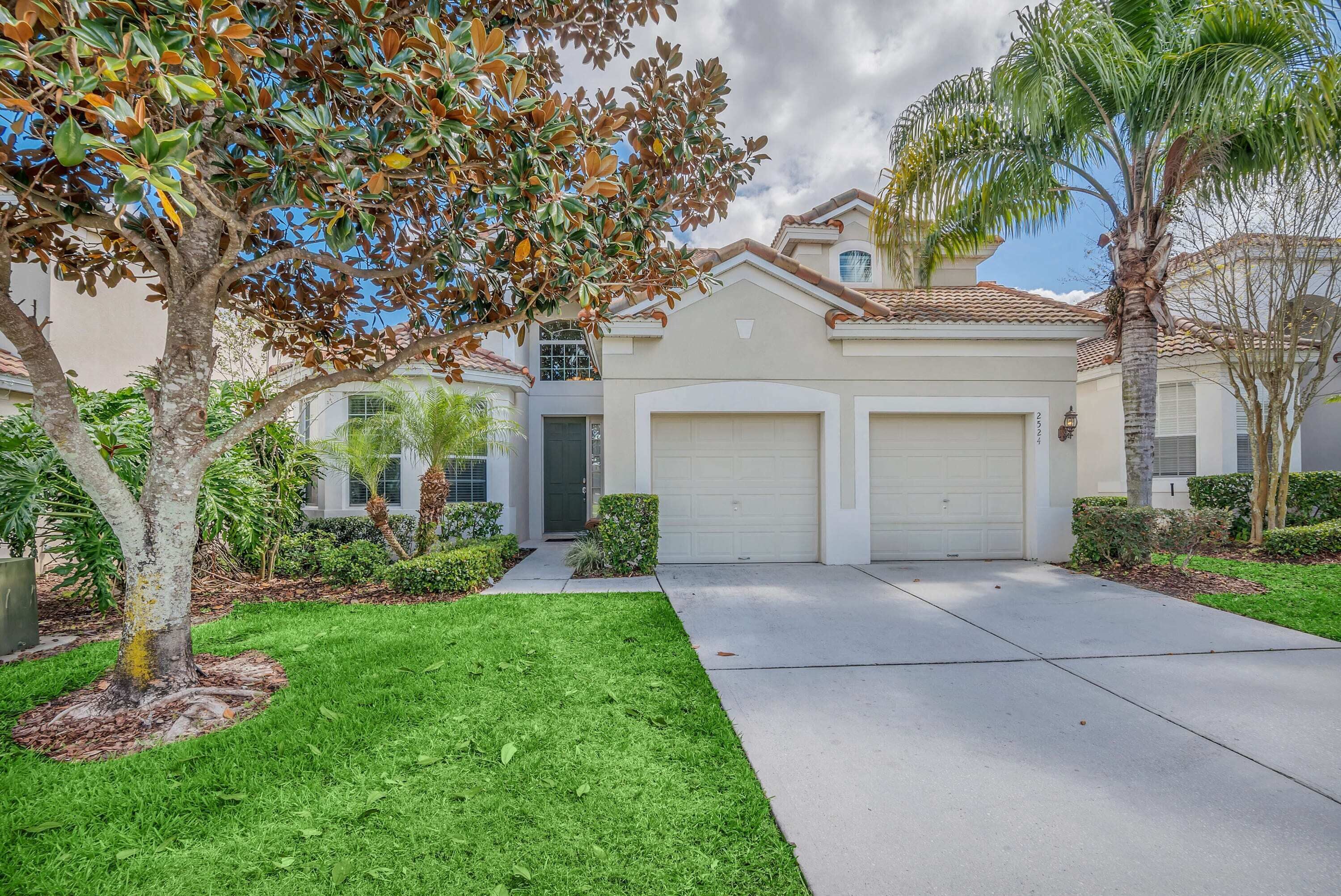 A residential house with a front yard, two garage doors, and a well-maintained lawn.