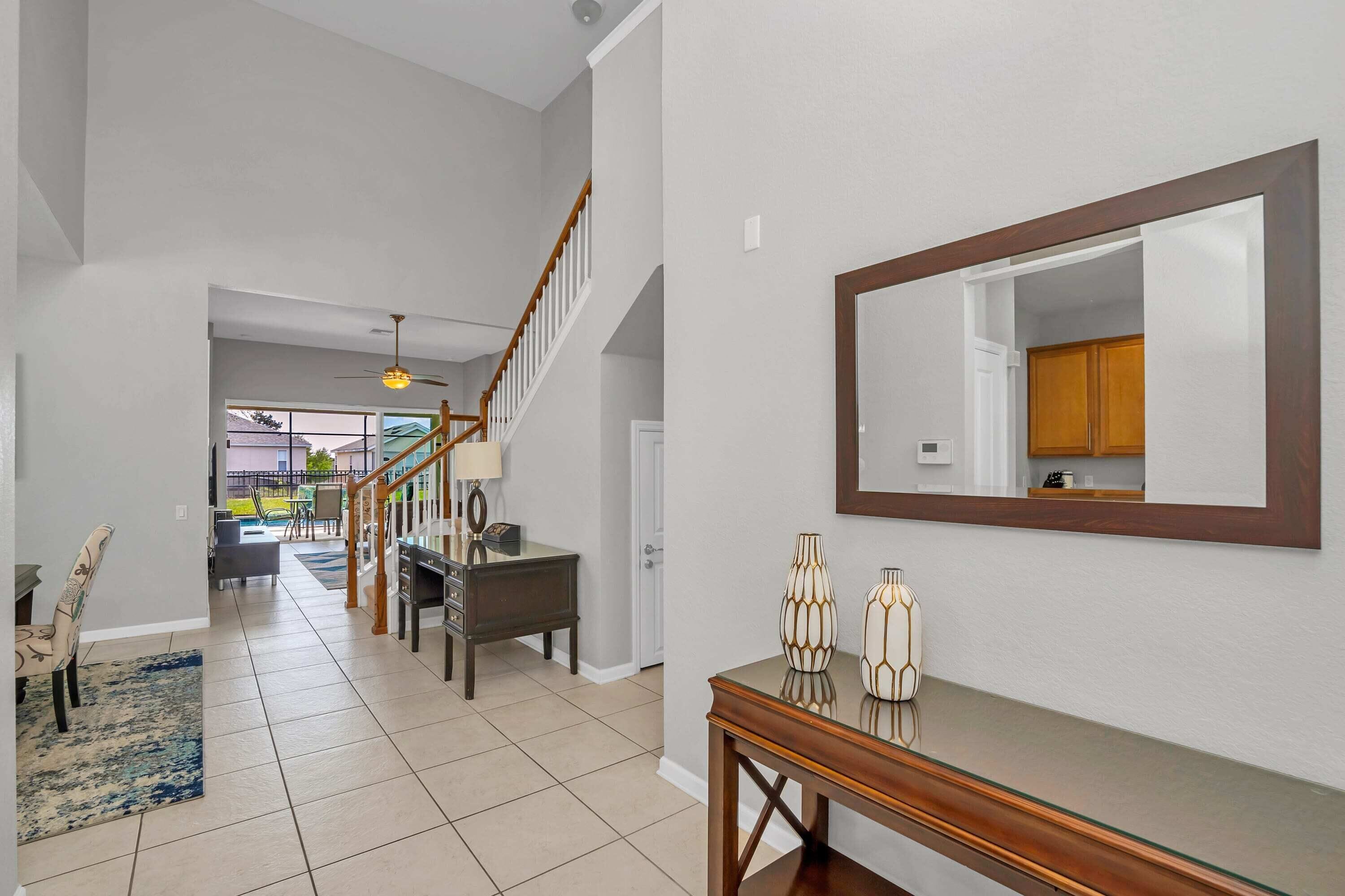 A spacious hallway with a staircase, a dining area, and a large mirror on the wall.