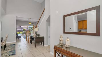 A spacious hallway with a staircase, a dining area, and a large mirror on the wall.