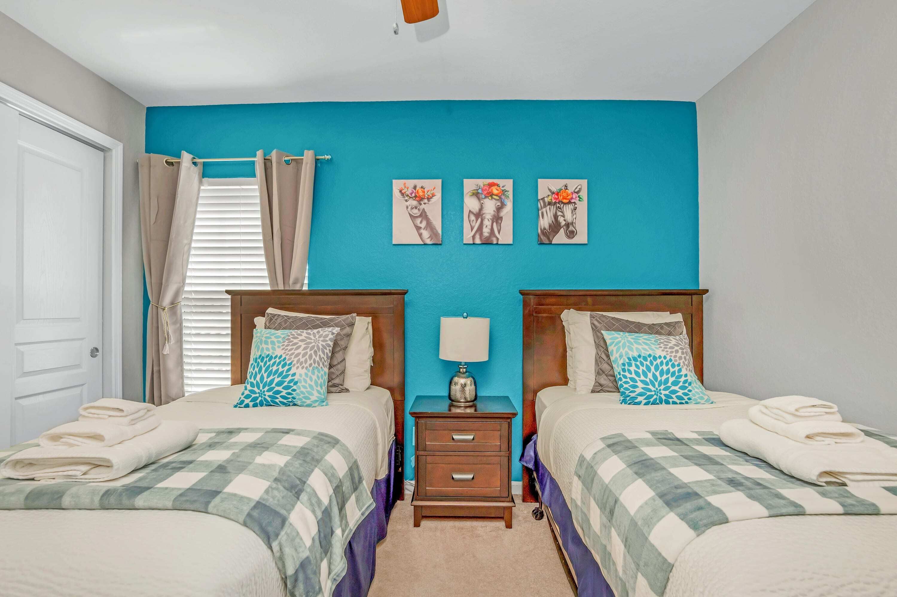 A twin bedroom with two beds, a nightstand, and a wall with three framed pictures.