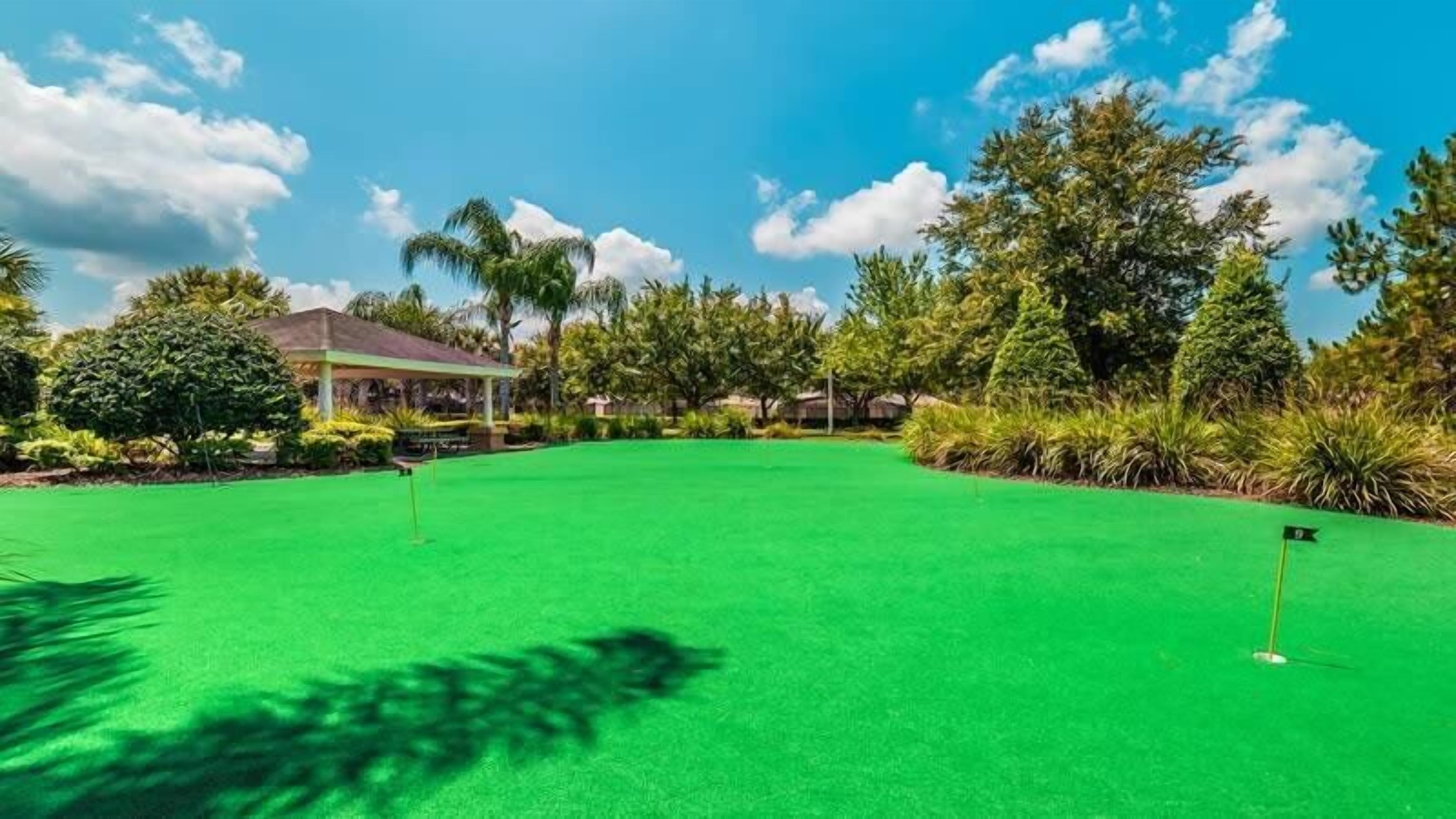Ein Golfplatz mit blauem Himmel, einer Laube und üppigem Grün.