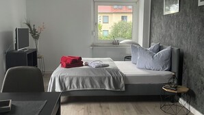 A modern bedroom with a bed, a desk, and a window. - Ferienzimmer (Zwickau)