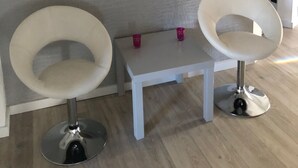 A modern room with two white chairs and a small table, a zebra-striped artwork on the wall, and a textured wall. - Ferienzimmer (Zwickau)