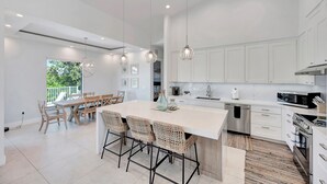 A modern kitchen with white cabinets, stainless steel appliances, and a central island with bar stools.
