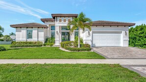 A modern two-story house with a white exterior, a garage, and a well-maintained lawn.