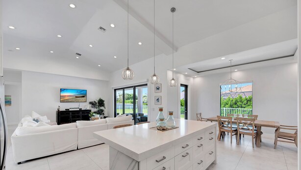 A modern kitchen with a large island, white cabinetry, and pendant lighting.