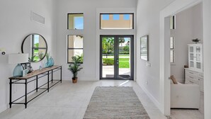 A modern hallway with a console table, mirrors, a potted plant, and a view to the outside.