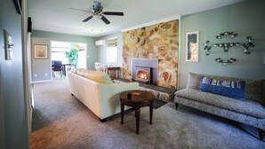 Ein Wohnzimmer mit Steinwand, Kamin, Deckenventilator und einer Couch.