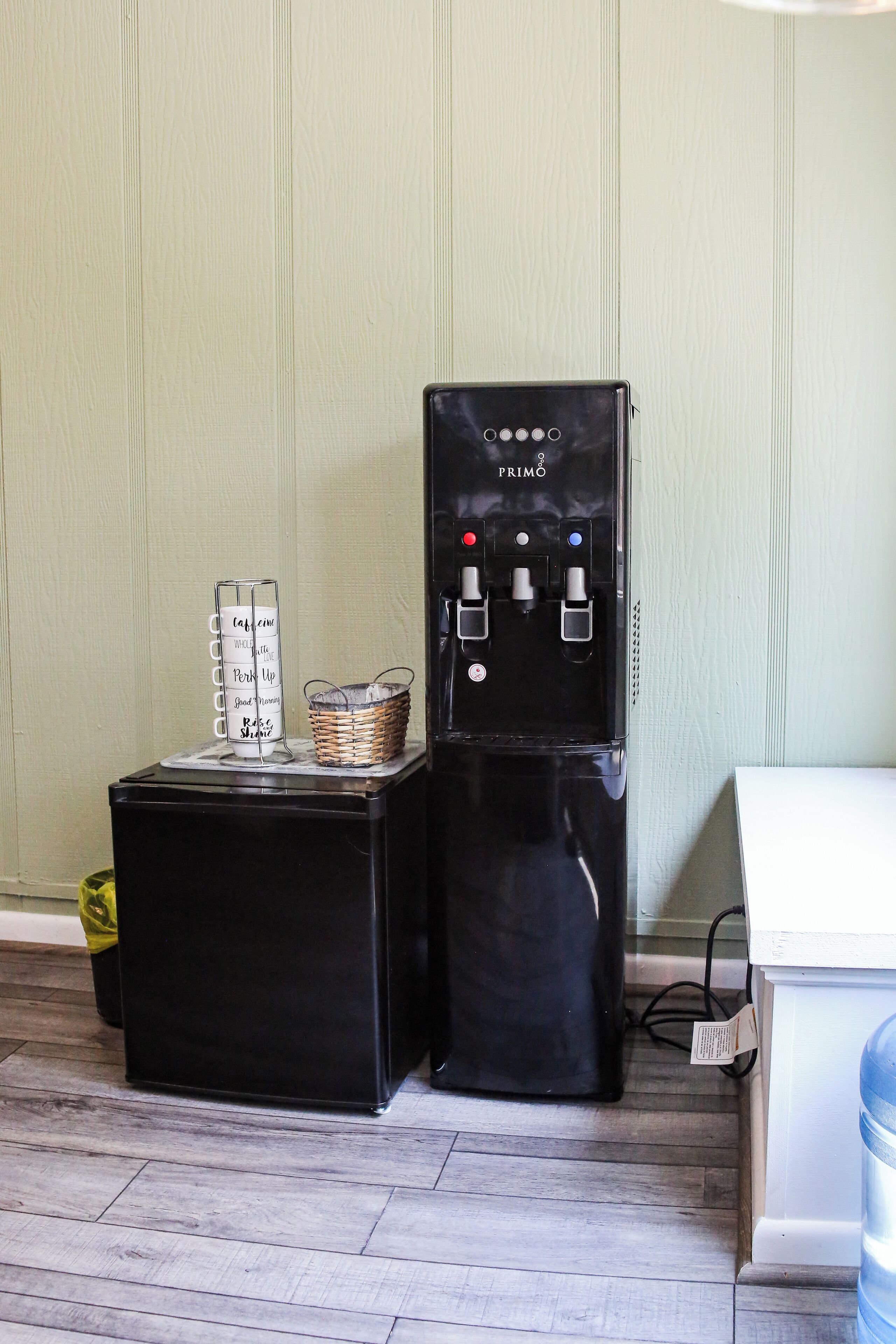 Un distributeur d’eau et une pile de tasses sur une table.
