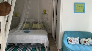 A room with a bunk bed, a lower bed with a striped rug, a blue sofa with patterned cushions, and a small wall clock. - Bungalow with private Jacuzzi (Saint-François)