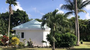A white house with a blue roof, surrounded by palm trees and various plants. - Bungalow with private Jacuzzi (Saint-François)