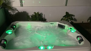 A hot tub with multiple jets, surrounded by plants. - Bungalow with private Jacuzzi (Saint-François)
