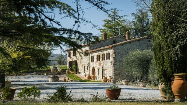 A stone building with multiple windows and a gravel driveway. - Villa Radda by MMega (Gaiole In Chianti)