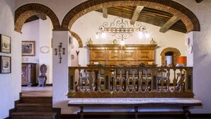 A room with a wooden bench, a decorative railing, and a chandelier. - Villa Radda by MMega (Gaiole In Chianti)