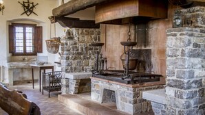 A stone-walled kitchen with a large wooden beam, stone steps, and a hanging basket. - Villa Radda by MMega (Gaiole In Chianti)