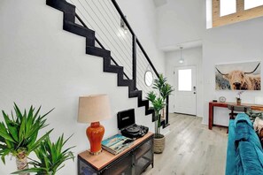 A modern living room with a staircase, a sofa, a coffee table, and a lamp.