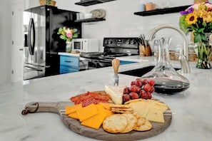 A kitchen counter with a charcuterie board featuring various cheeses, cured meats, and crackers.