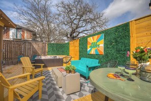 Un patio trasero con terraza de madera, mobiliario exterior, un jacuzzi y un mural.