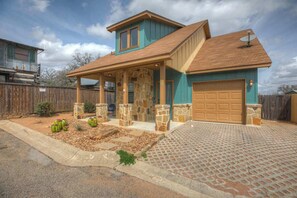 A two-story house with a stone facade, a covered porch, and a garage. - Hottub-Deck-Firepit-Cornhole! (Fredericksburg)