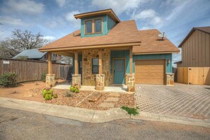 A two-story house with a stone facade, a blue door, and a garage.
