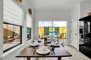 Un comedor con una mesa preparada para cuatro, ventanas amplias y vistas al exterior.